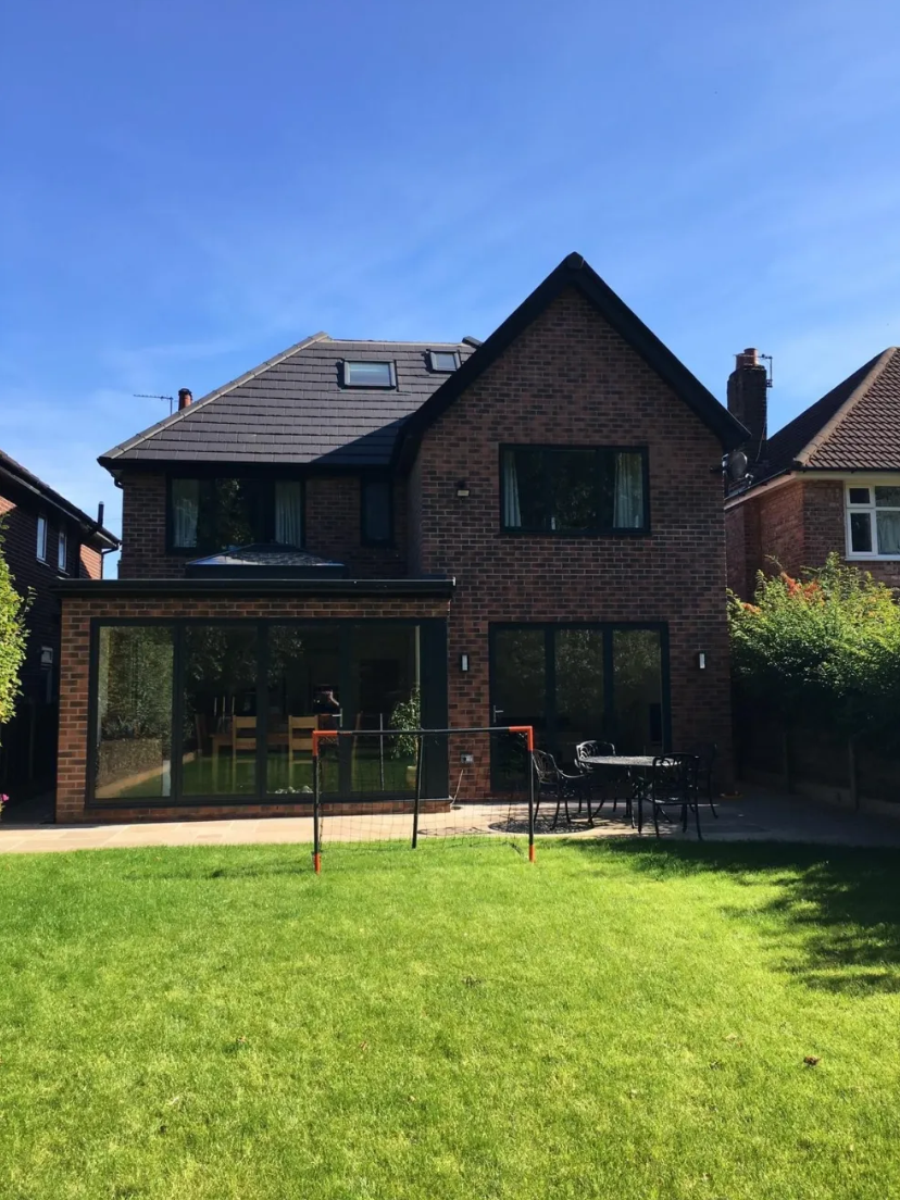 Brick family home with large glass-walled extension and sunny landscaped garden